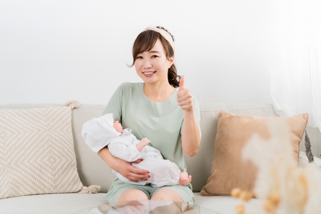 赤ちゃんを抱っこしている笑顔の女性の画像